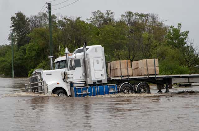 A truck drives into floodwater.