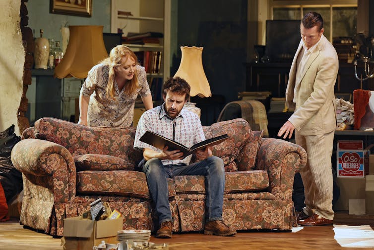 Production image. Three adults look through a photo album.