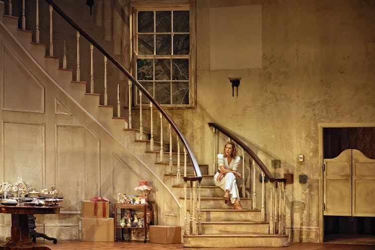 A woman sits on a sweeping staircase.