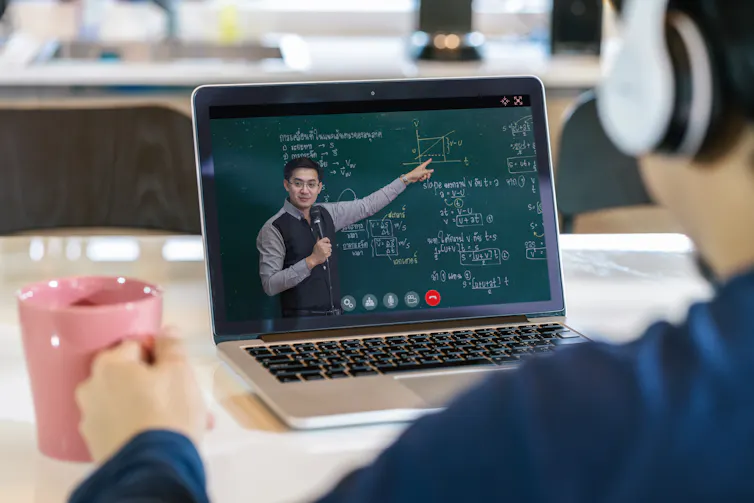 A student listens to an online lecture that is being broadcast on his laptop