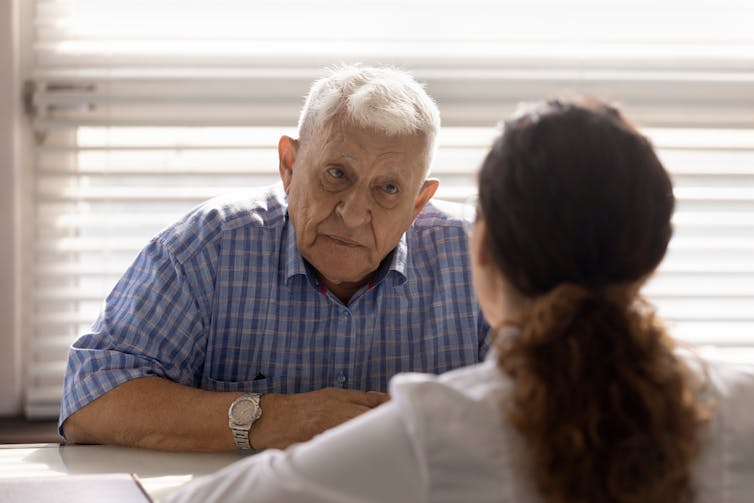 A senior man talks with a doctor.
