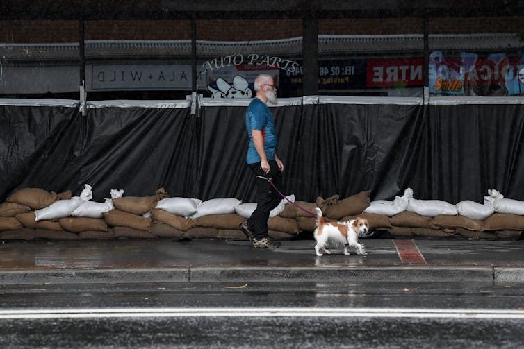 A man walks past a sand-bagged business