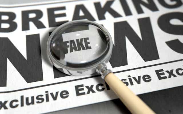 A newspaper showing the words "breaking news" with a magnifying glass over the word "fake".