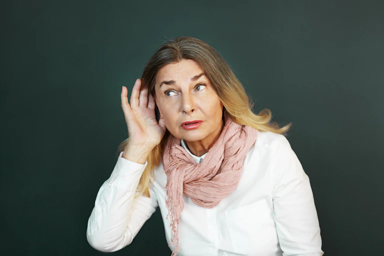 Woman holding her hand up to her ear to hear better.