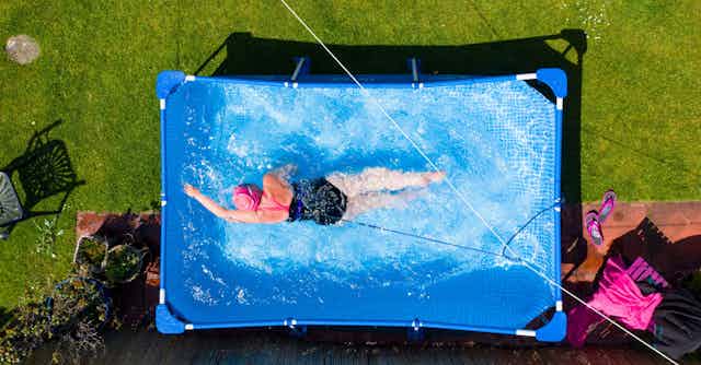 A woman swims in a garden paddling pool.