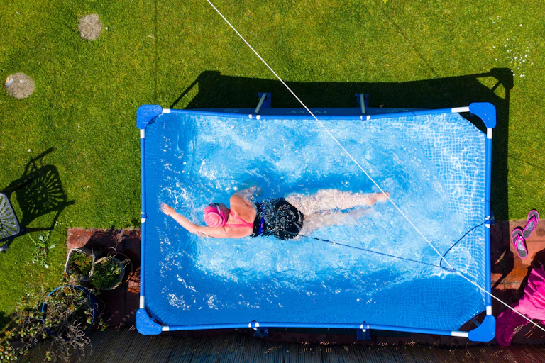 A woman swims in a garden paddling pool.