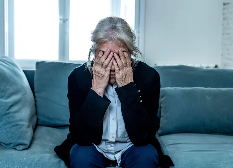 A woman covering her face with her hands.