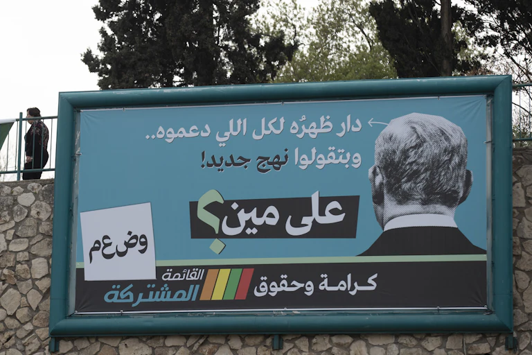 Large billboard showing the back of the prime minister, Benjamin Netanyahu's head and a an anti-Netanyahu message in message in Arabic script.
