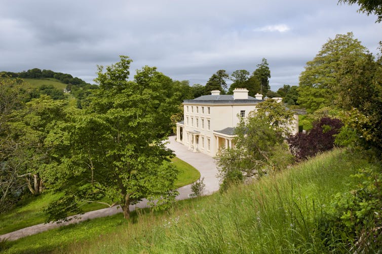 White manor home surrounded by green.