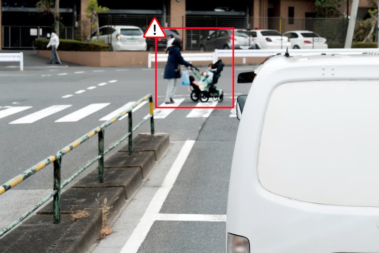 A red alert box around a women on a zebra crossing pushing a pram