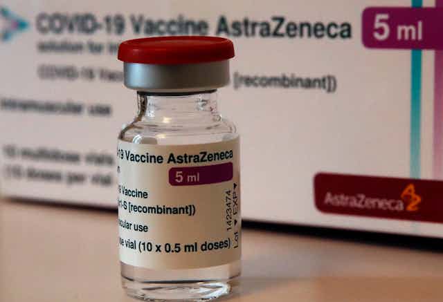 A vial of the AstraZenaca vaccine in front of a box.