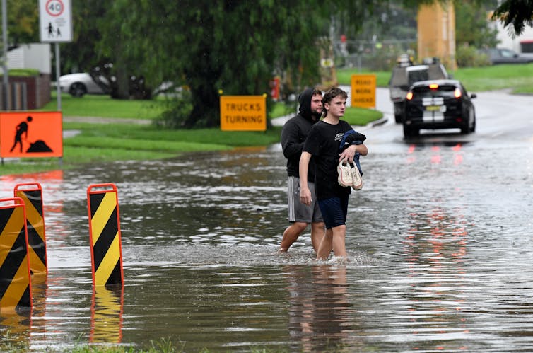 two men stand in floodwaters