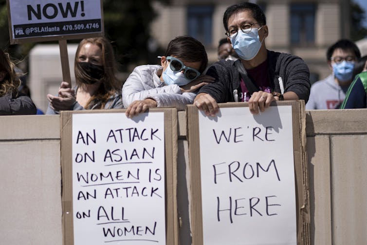 Two Asian men hold signs at a ‘stop Asian hate’ rally outside the Georgia state capitol in Atlanta.