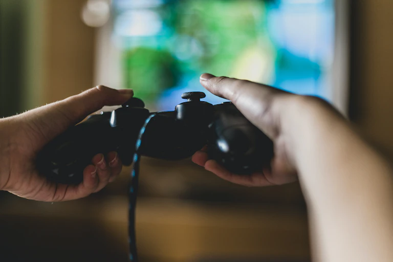 Gambar dari dekat tangan yang sedang memegang stik video game