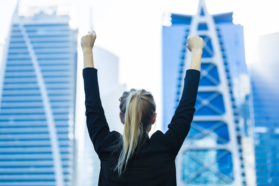 Young female executive with her hands in the air in front of some skyscrapers