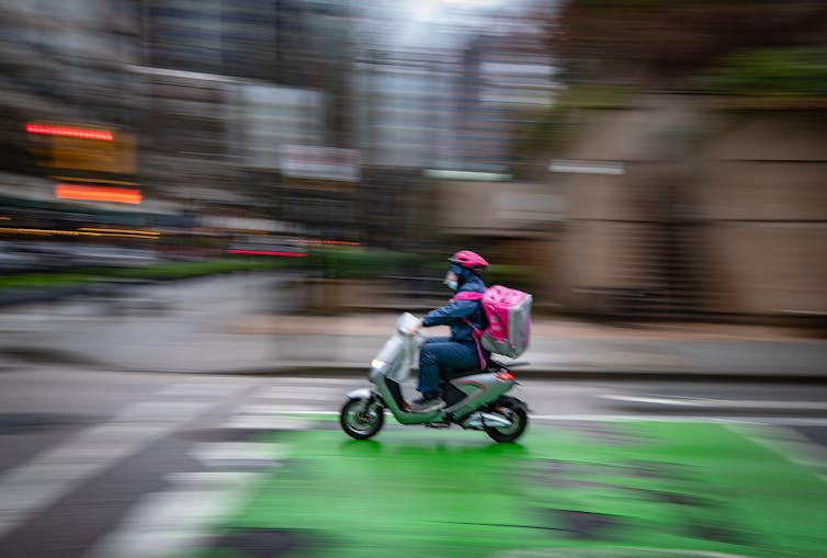 A food delivery worker rides an electric bike