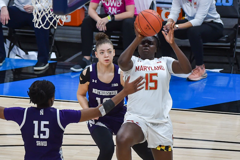 A female basketball player attempts to shoot a basketball over another female player.