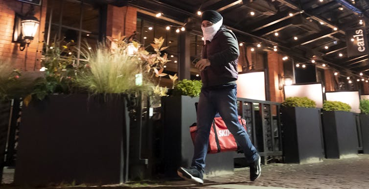 A food delivery person wears a protective face mask to prevent the spread of COVID-19 as he picks up food.