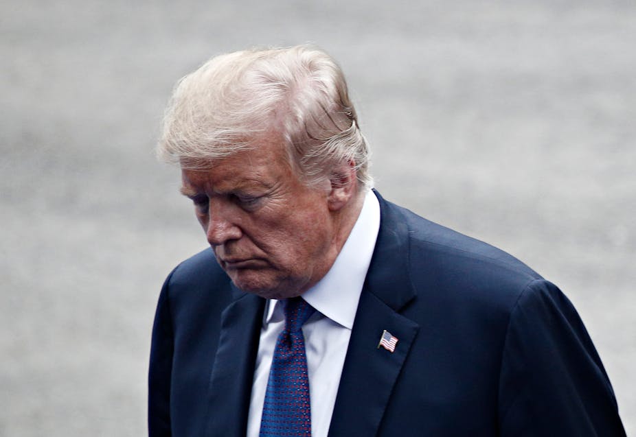 Donald Trump looking down in a dark suit