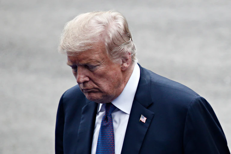 Donald Trump looking down in a dark suit