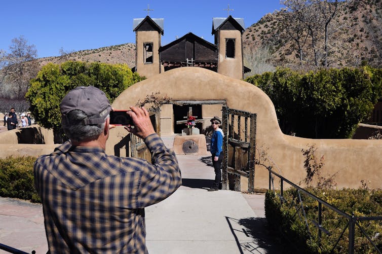 A tourist takes a photo of the Catholic chapel El Santuario de Chimayo in Chimayo, New Mexico.