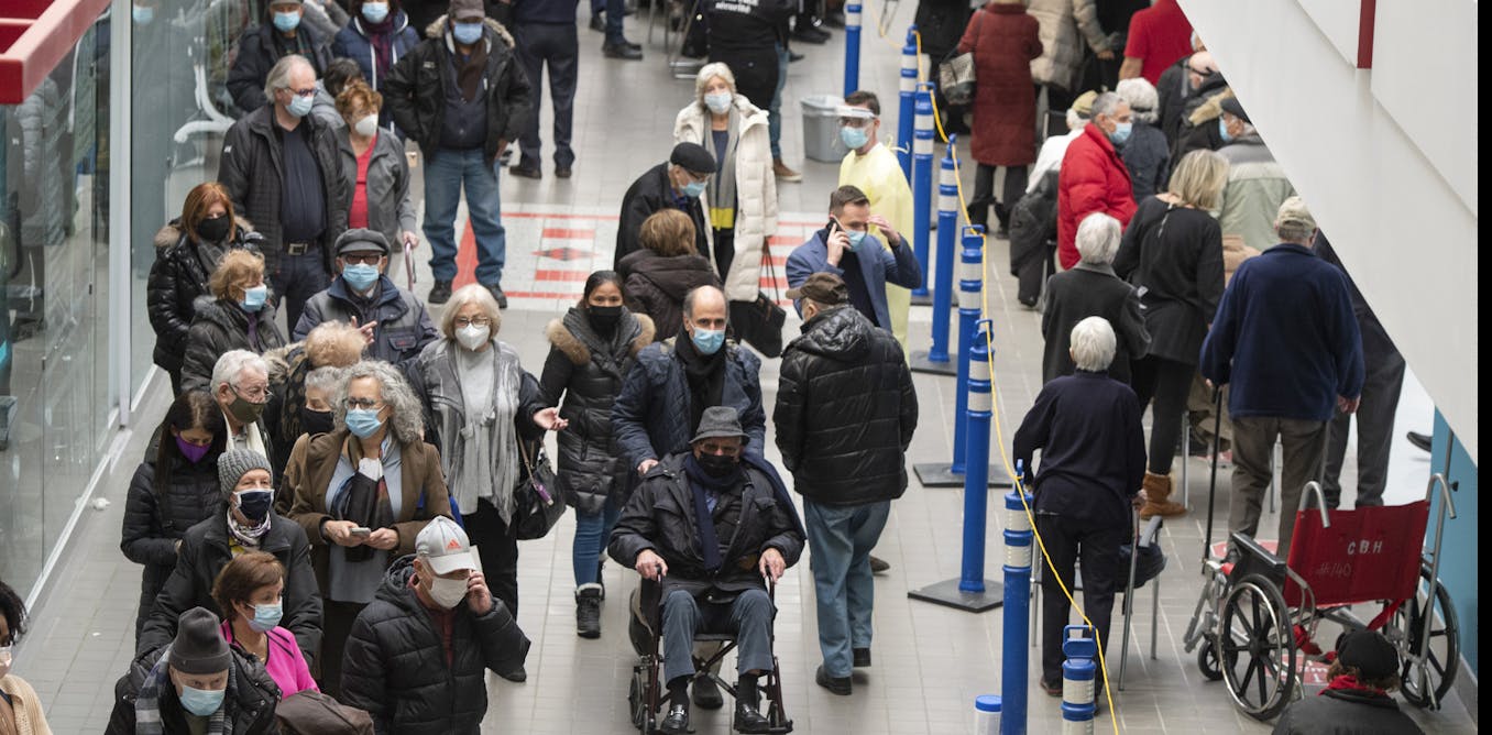 Group of masked people waiting in line to get vaccinated