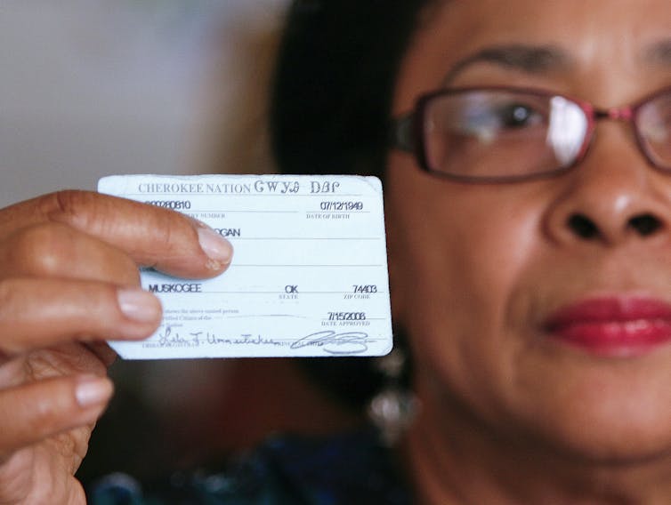 A woman who descends from Cherokee Freedmen holding her tribal ID card.