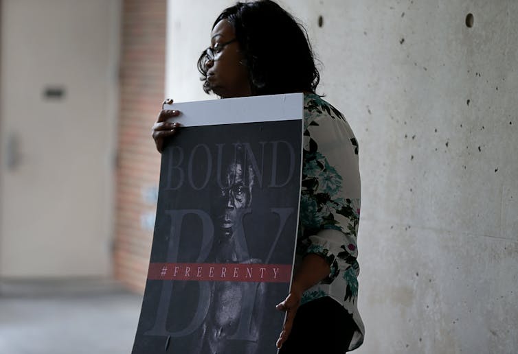 woman holds historical photo of enslaved Black man