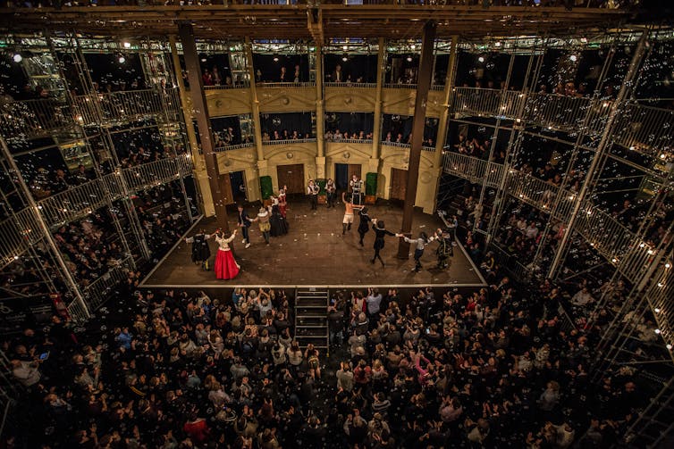Lots of people in the audience watching a production on stage.