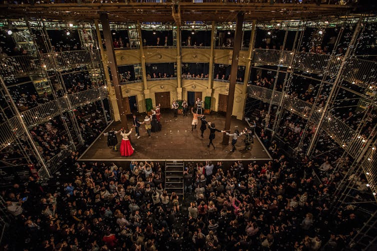 Lots of people in the audience watching a production on stage.