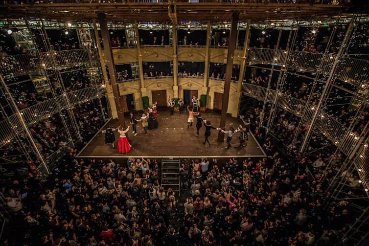 Lots of people in the audience watching a production on stage.