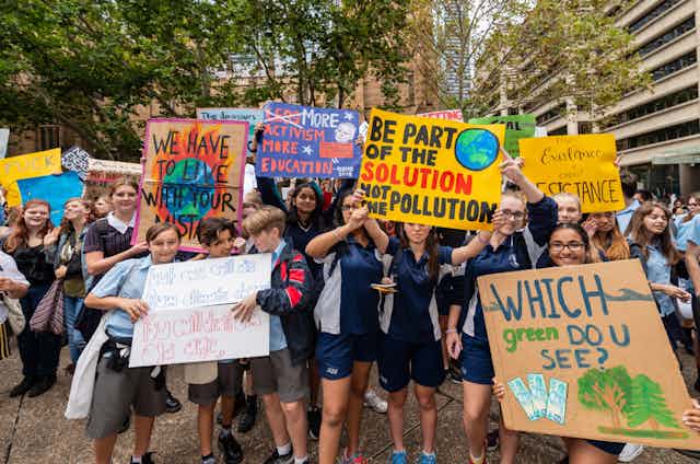 Students in school uniform hold up climate change signs at a protest