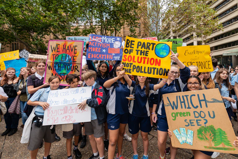 Students in school uniform hold up climate change signs at a protest