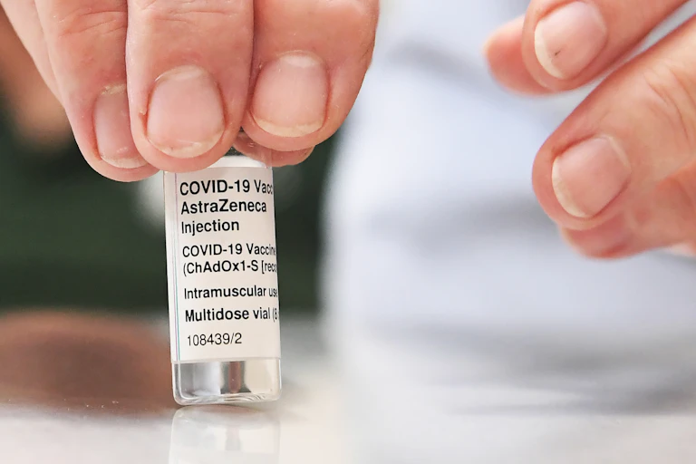 A hand holds a vial of the AstraZeneca vaccine.