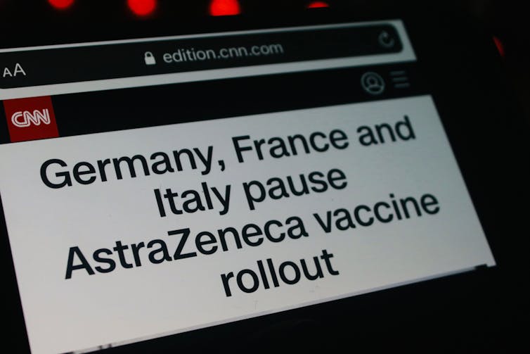 Vaccine news about vaccine pause on smartphone screen