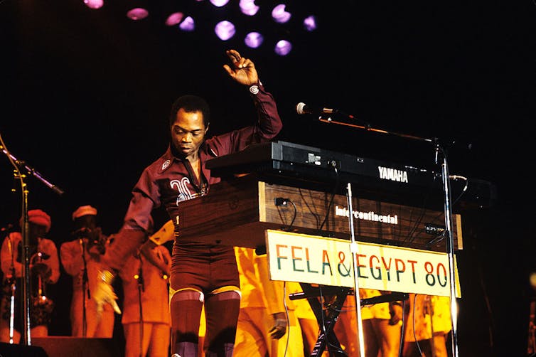 A man standing on stage in partly behind keyboards.