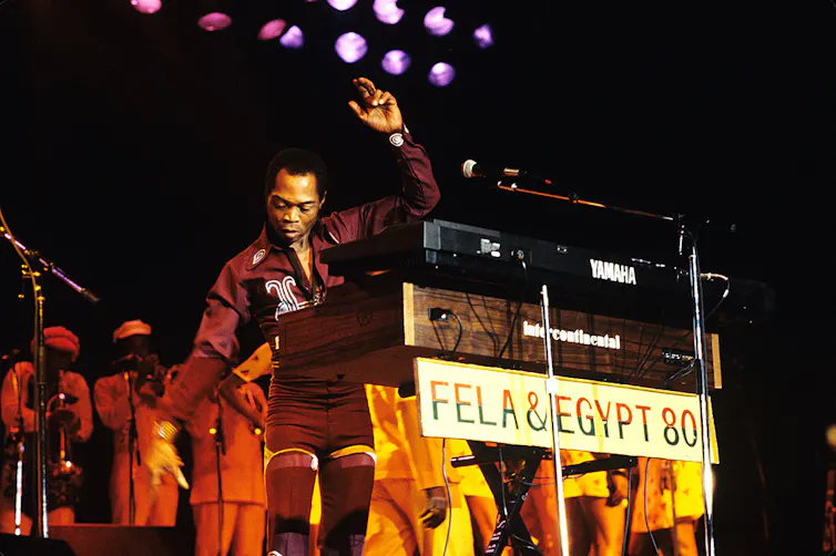 A man standing on stage in partly behind keyboards.
