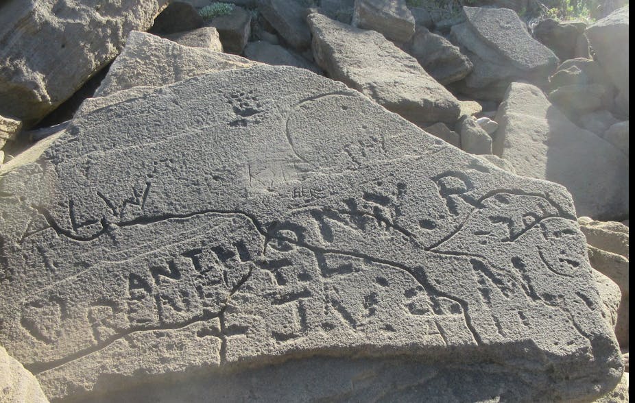 Letters and symbols are etched into a grey rock surface