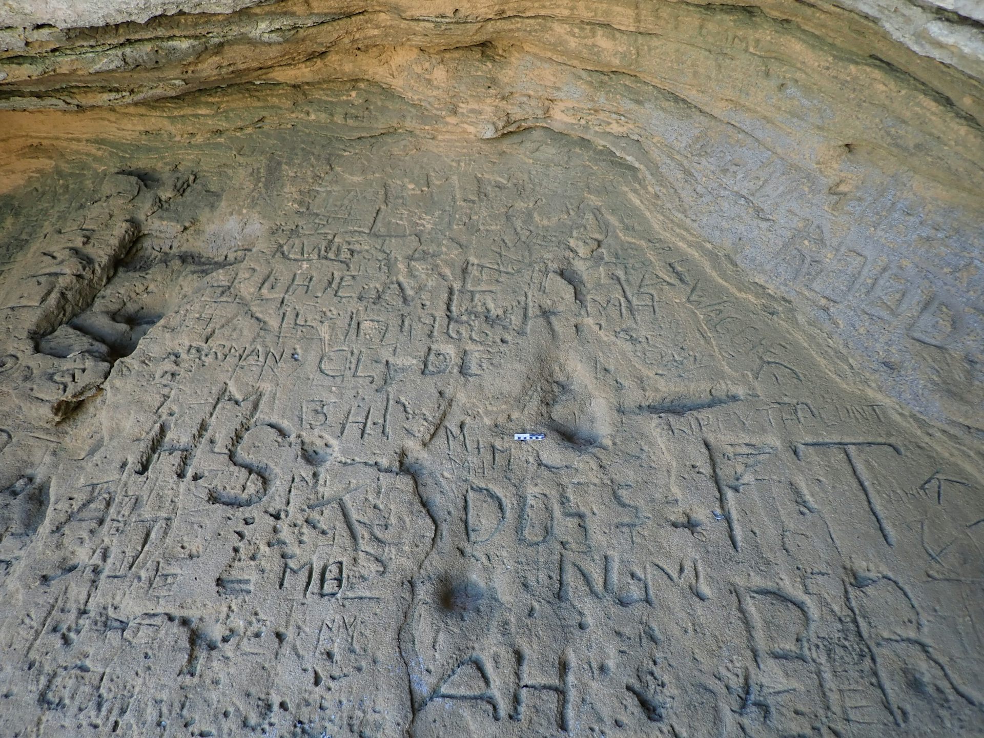 A slightly bumpy large slab of what looks like concrete is covered in letters and etchings