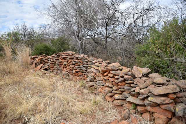 Orderly piles of stones and rocks line an area surrounded by trees and grasses