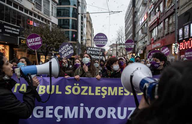 Turkish women demonstrate in the streets of Istanbul carrying banners and holding megaphones.