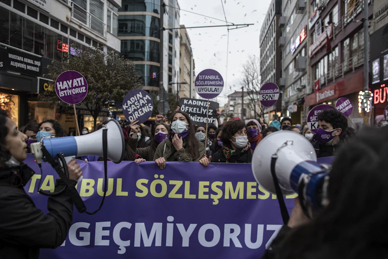 Turkish women demonstrate in the streets of Istanbul carrying banners and holding megaphones.