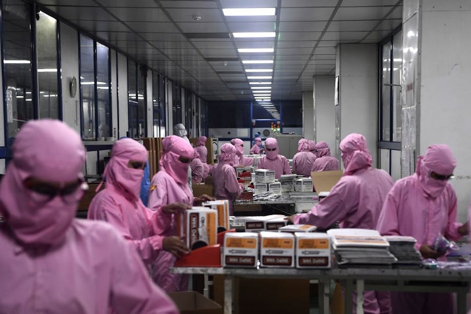 Workers wearing protective clothing pack syringes at India's largest producer.
