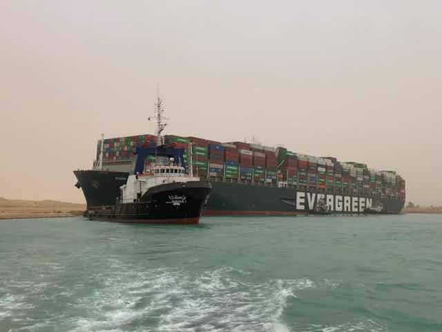 A vast container ship wedged between two banks of the canal.