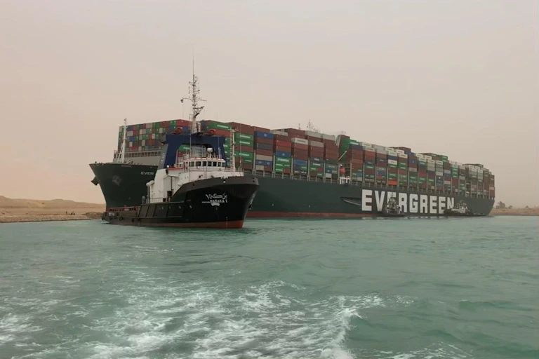 A vast container ship wedged between two banks of the canal.