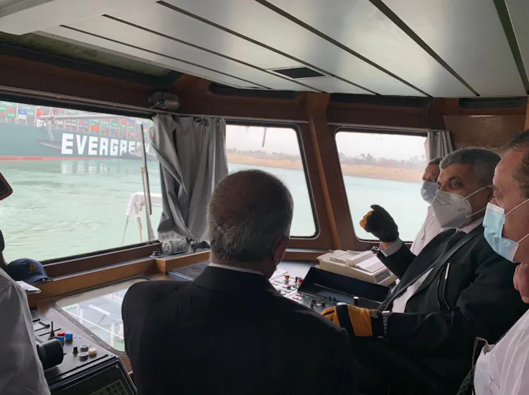 Officials survey the grounded ship from the bridge of a smaller ship.