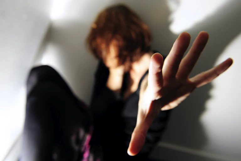 Woman in a corner holds out her hand in self-defense