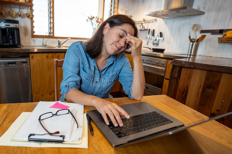 Woman working at computer at kitchen table.