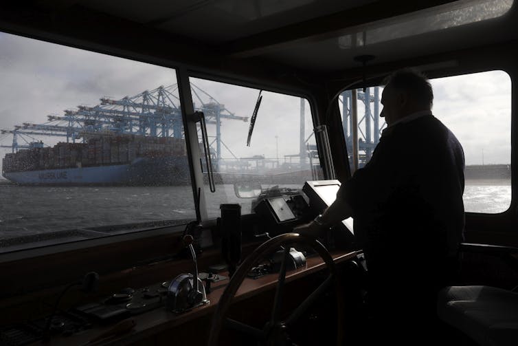 Looking at a large blue container ship through the window of a smaller boat