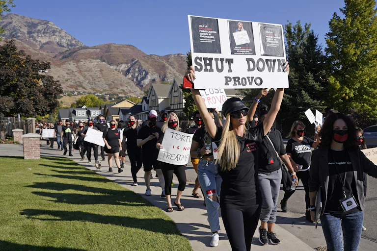 Paris Hilton leading a demonstration while holding a "Shut down Provo" sign.